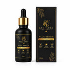 A black glass dropper bottle of Rahi Luxa Organic Face Serum with a gold collar, shown next to its black and gold retail box on a white background.